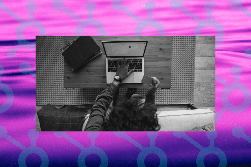 Black and white photo of a person using their credit card to make an online donation. This is stacked on a purple background with the HubSpot logo repeating, signifying a connection to utilizing HubSpot for fundraising.